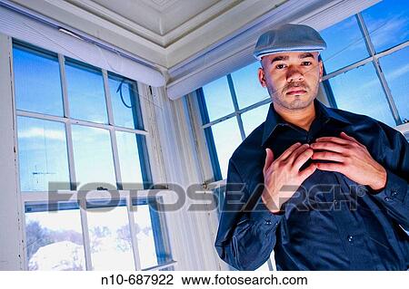 Young Hispanic man, wearing a cap on his head, posing in front of several windows. View Large Photo Image Stock Image - Young Hispanic man, wearing a cap on his head, posing in front of several windows.. Fotosearch