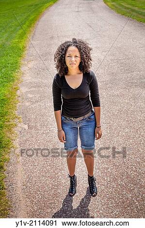 Stock Image - Young Hispanic woman in a park.. Fotosearch