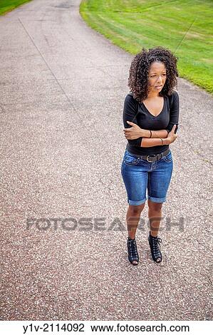 Stock Image - Young Hispanic woman in a park.. Fotosearch
