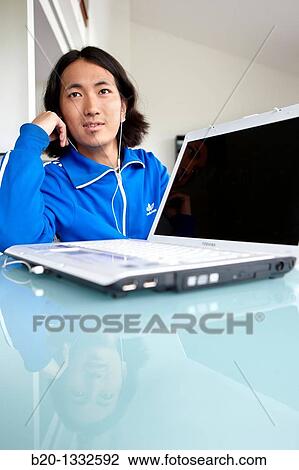 Young Japanese man with laptop computer in room View Large Photo Image Stock Image - Young Japanese man with laptop computer in room. Fotosearch