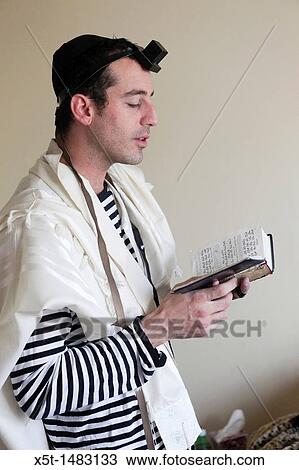 Stock Image - Young Jewish man with tallith and Tefillin. Fotosearch