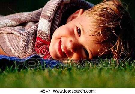 Young kid lying on the garden grass View Large Photo Image Stock Photo - Young kid lying on the garden grass. Fotosearch