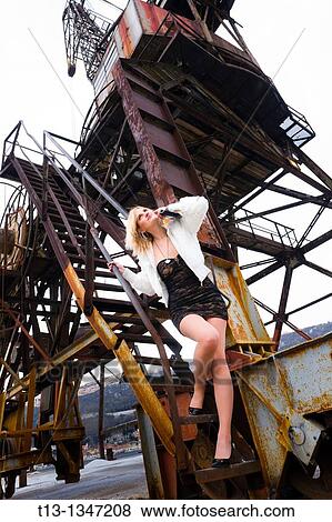 Young lady with a purse in hand is posing on the rotten old harbor derrick View Large Photo Image Stock Photo - Young lady with a purse in hand is posing on the rotten old harbor derrick. Fotosearch