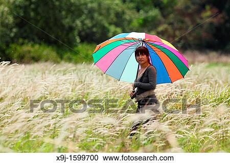 Young lady with colorful umbrella standing in the grass field. View Large Photo Image Stock Image - Young lady with colorful umbrella standing in the grass field.. Fotosearch