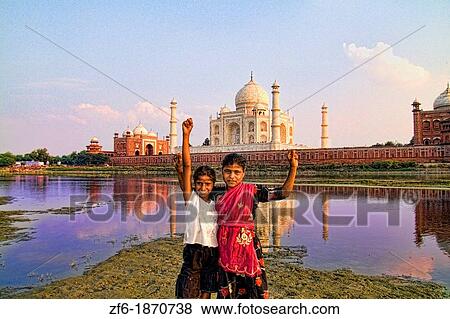 Stock Photo - Young local children celebrating at World famous Taj Mahal at sunset from Yamuna River with reflection in town of Agra India. Fotosearch