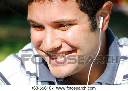 Stock Photo - young male adult listening to music with earphone. Fotosearch