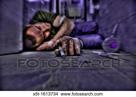 Picture - Young male Drug addict shooting up in a soiled bathroom. Fotosearch
