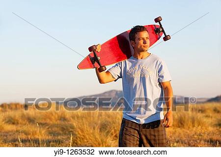 Stock Image - Young Male posing with his skate board. Fotosearch