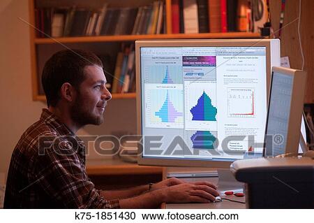 Stock Image - Young male using computer graphs. Fotosearch