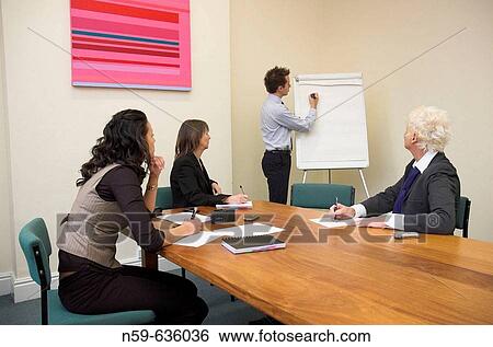 Young man about to start a presentation using a flip chart at a small business meeting. View Large Photo Image Stock Photograph - Young man about to start a presentation using a flip chart at a small business meeting.. Fotosearch