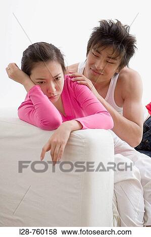 Stock Photo - Young Man and Woman sitting on sofa.. Fotosearch