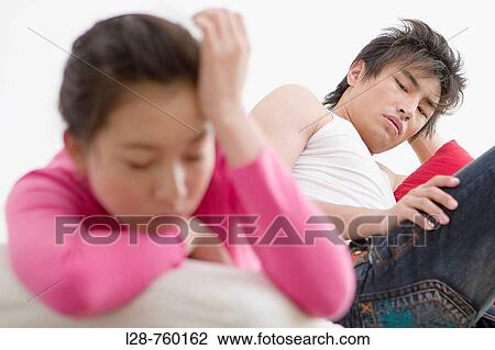 Stock Image - Young Man and Woman sitting Sadness on sofa. Fotosearch