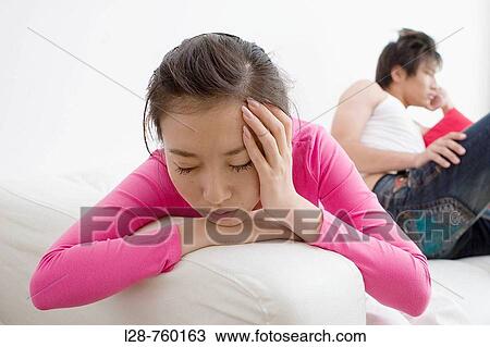 Stock Image - Young Man and Woman sitting Sadness on sofa. Fotosearch