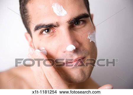Young man applying facial cream. View Large Photo Image Picture - Young man applying facial cream.. Fotosearch