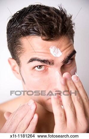 Young man applying facial cream. View Large Photo Image Picture - Young man applying facial cream.. Fotosearch