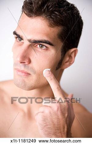 Stock Photo - Young man applying facial cream.. Fotosearch