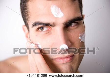 Young man applying facial cream. View Large Photo Image Stock Photograph - Young man applying facial cream.. Fotosearch
