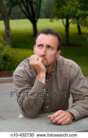 Young man, at a park, leaning on a ledge View Large Photo Image Stock Image - Young man, at a park, leaning on a ledge. Fotosearch
