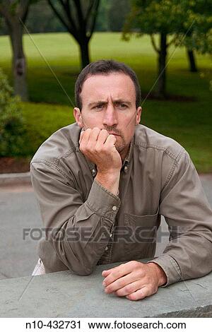 Young man, at a park, leaning on a ledge View Large Photo Image Stock Image - Young man, at a park, leaning on a ledge. Fotosearch