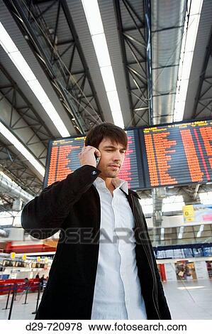 Young man at the airport talking on cell phone View Large Photo Image Stock Photo - Young man at the airport talking on cell phone. Fotosearch