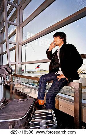 Young man at the airport talking on cell phone View Large Photo Image Stock Photograph - Young man at the airport talking on cell phone. Fotosearch