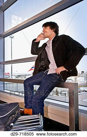 Young man at the airport talking on cell phone View Large Photo Image Stock Photography - Young man at the airport talking on cell phone. Fotosearch