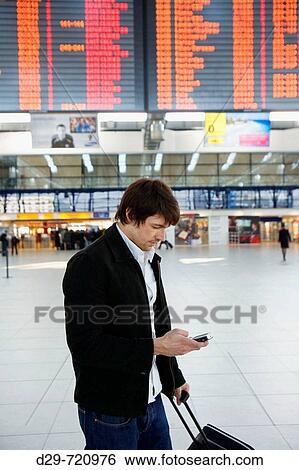 Stock Photograph - Young man at the airport with cell phone. Fotosearch