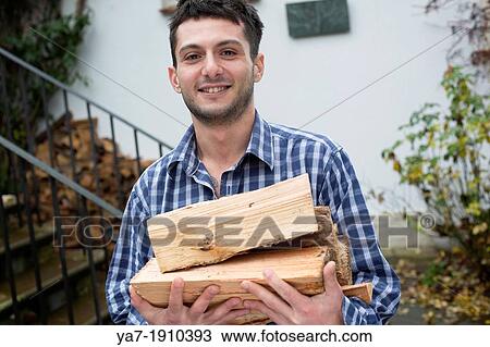 Stock Image - Young Man Carrying Chopped Wood. Fotosearch