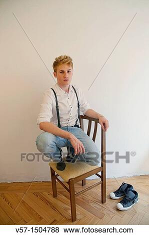 Young man climbed on a chair View Large Photo Image Stock Photo - Young man climbed on a chair. Fotosearch