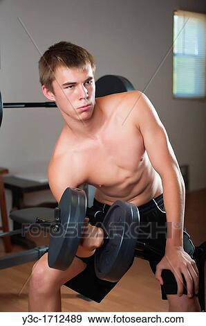 Young man curling handbell at fitness studio View Large Photo Image Stock Photo - Young man curling handbell at fitness studio. Fotosearch