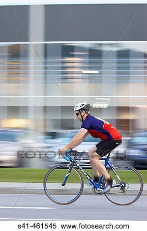 Young man cycling, blurred urban background View Large Photo Image Stock Photography - Young man cycling, blurred urban background. Fotosearch