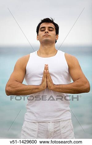 Stock Image - Young man doing yoga at the beach. Fotosearch