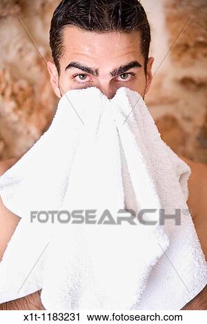 Stock Image - Young man drying his face.. Fotosearch