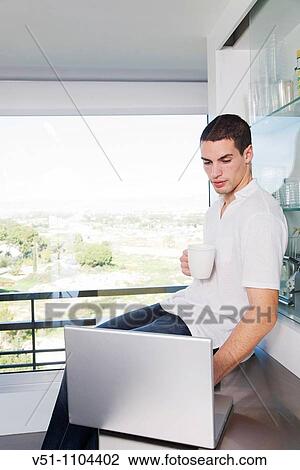 Young man having breakfast in the kitchen with laptop View Large Photo Image Stock Image - Young man having breakfast in the kitchen with laptop. Fotosearch