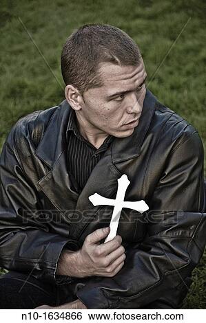 Young man holding a cross View Large Photo Image Stock Photograph - Young man holding a cross. Fotosearch