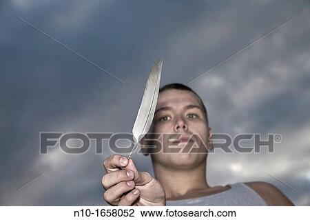 Young man holding a feather View Large Photo Image Stock Image - Young man holding a feather. Fotosearch