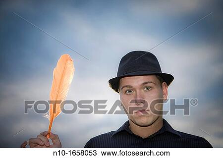 Young man holding a feather View Large Photo Image Stock Image - Young man holding a feather. Fotosearch