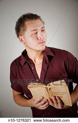 Young man holding a French book View Large Photo Image Stock Image - Young man holding a French book. Fotosearch