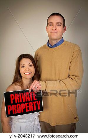 Young man holding a "Private Property" sign in front of his wife. View Large Photo Image Stock Photo - Young man holding a "Private Property" sign in front of his wife.. Fotosearch