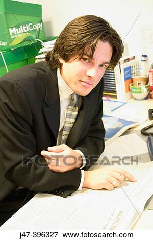 Young man in a suit sitting with a newspaper, smiling into camera View Large Photo Image Stock Photo - Young man in a suit sitting with a newspaper, smiling into camera. Fotosearch