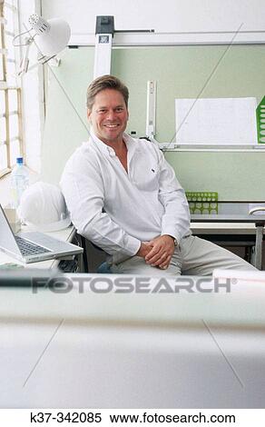 Young man in design studio sitting at draughting table. Proud small business owner View Large Photo Image Stock Photography - Young man in design studio sitting at draughting table. Proud small business owner. Fotosearch