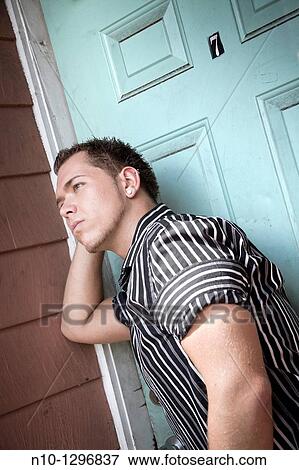 Stock Photo - Young man in front of a green door. Fotosearch