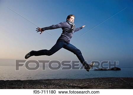 Young man jumping along the seashore at dawn View Large Photo Image Stock Image - Young man jumping along the seashore at dawn. Fotosearch