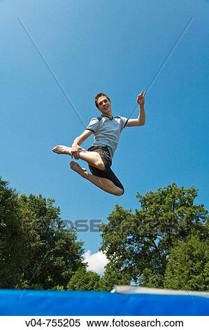 Young man jumping high on a trampoline outdoor View Large Photo Image Stock Photography - Young man jumping high on a trampoline outdoor. Fotosearch