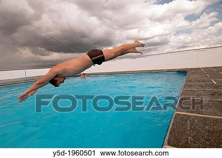 Stock Image - young man jumping to the swimming pool, swimming pool on the roof of skyscraper - residential building in Geneva, Switzerland, Europe. Fotosearch