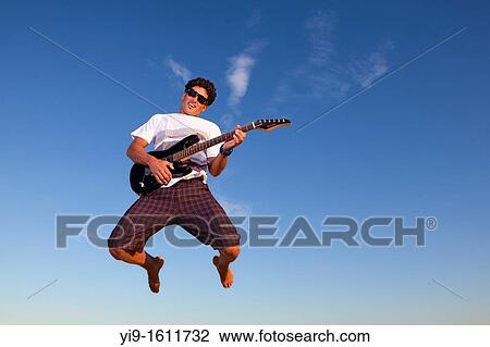 Stock Image - Young man jumping with electric guitar. Fotosearch