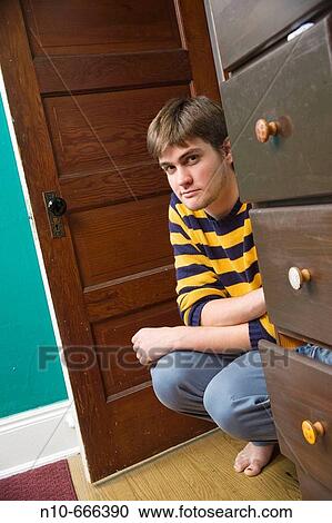 Young man kneeling on the floor in his bedroom. View Large Photo Image Stock Image - Young man kneeling on the floor in his bedroom.. Fotosearch