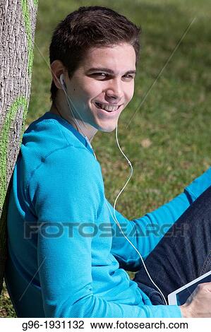 Stock Image - Young man listening music with earphones. Fotosearch