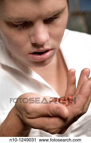 Young man looking at pills in his hand View Large Photo Image Stock Image - Young man looking at pills in his hand. Fotosearch