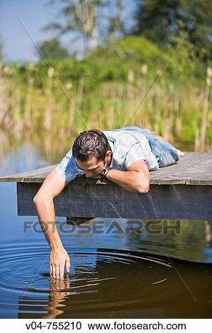 Young man lying on a footbridge at a lake making bubbles View Large Photo Image Stock Image - Young man lying on a footbridge at a lake making bubbles. Fotosearch